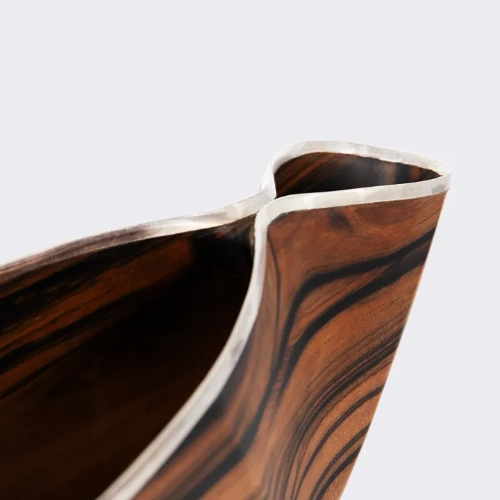 Handcrafted wood centerpiece with an organic wave shape and polished silver rim, luxury artisan design from Laos.
