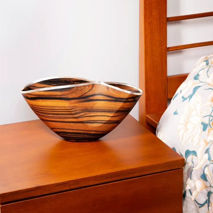 Handcrafted wood centerpiece with an organic wave shape and polished silver rim, luxury artisan design from Laos.