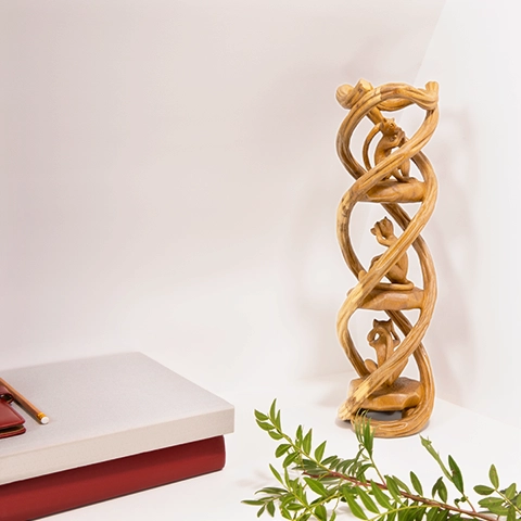 Elegant home office decor: Hand-carved 'Three Wise Monkeys' wooden totem displayed alongside books and greenery.