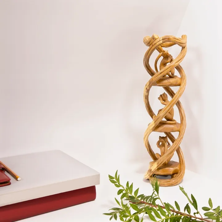 Elegant home office decor: Hand-carved 'Three Wise Monkeys' wooden totem displayed alongside books and greenery.