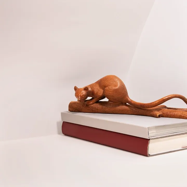 Handcrafted exotic wood sculpture of a stalking Fossa, a rare collectible wildlife art piece made in Madagascar.