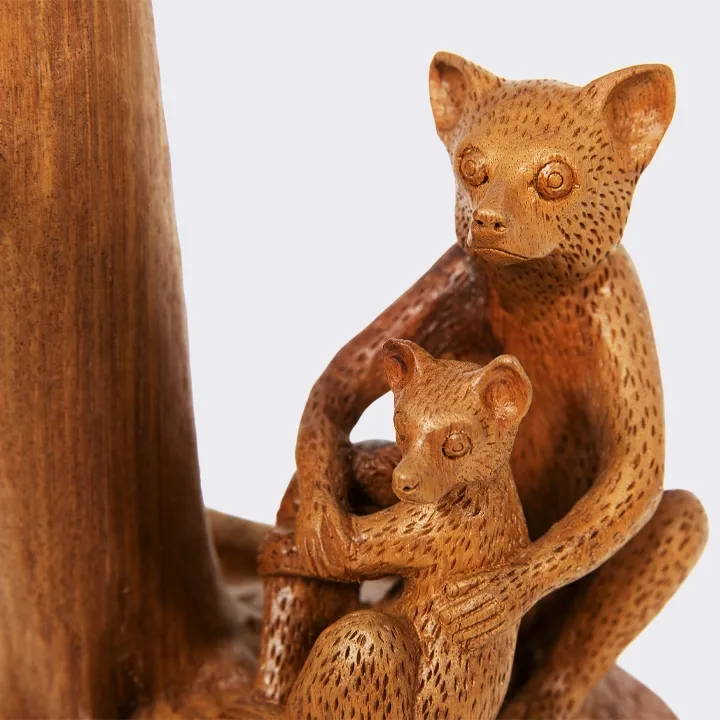  Elegant handcrafted statue from Madagascar, with a smooth finish, depicting a mother lemur and her baby sitting near a tree trunk.
