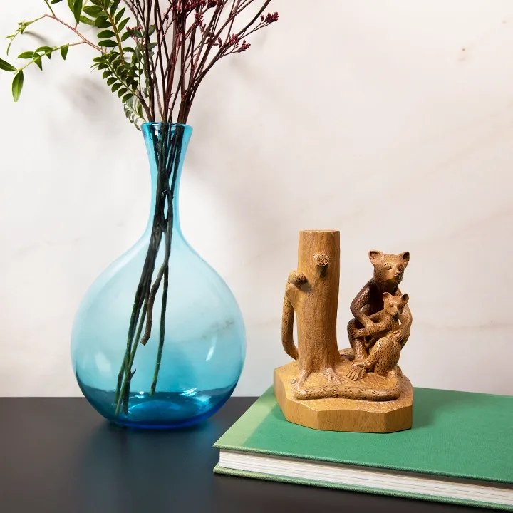  Elegant handcrafted statue from Madagascar, with a smooth finish, depicting a mother lemur and her baby sitting near a tree trunk.