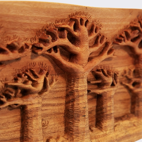 Close-up of a hand-carved wooden landscape, showing textured trunks and raised baobab canopies, highlighting the painstaking carving, finish, and refined details.