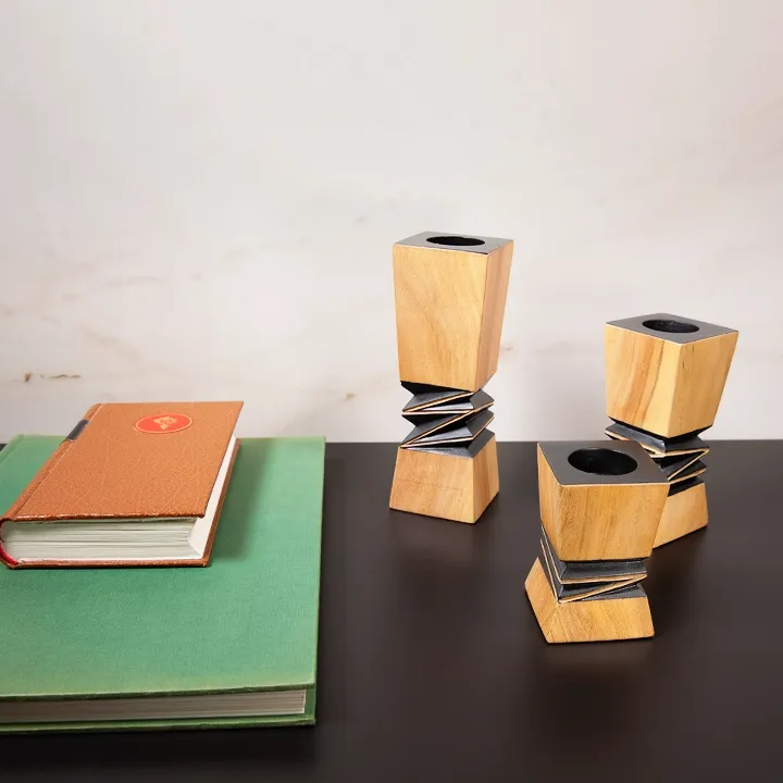Handcrafted architectural wooden candlestick with a contrasting black geometric relief in the center.