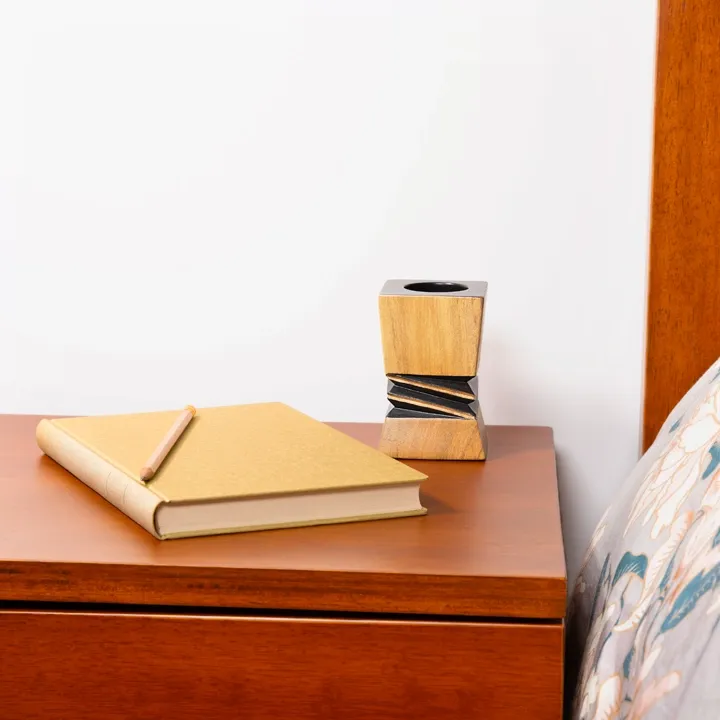 Contemporary bedroom décor: Handcrafted architectural wooden, candlestick with a contrasting black geometric relief in the center.