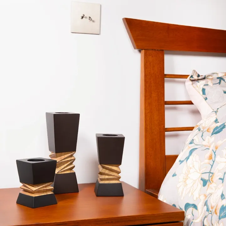Modern geometric bedroom decor: Set of three black and wood architectural candle holders displayed on a nightstand