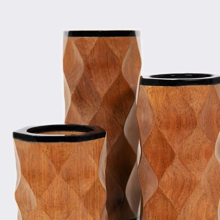 Handcrafted wooden candlestick with a contemporary black finish and tribal-inspired wavy carvings.