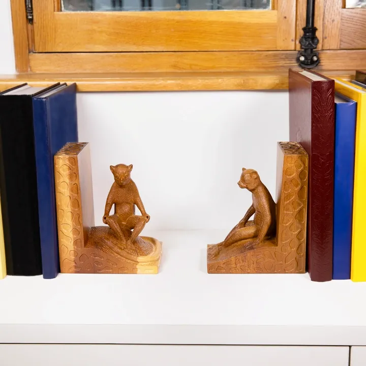 Pair of handcrafted bookends in wood, forming an L, with sculptures of lemurs in a seated position.