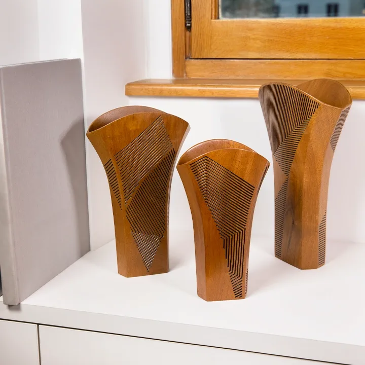 Modern minimalist shelf decor: Trio of flared exotic wood vases displayed in a bright, contemporary living space.
