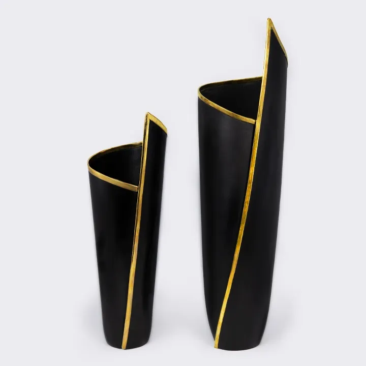 Set of two modern, asymmetrical vases in matte black metal, embellished with a striking brass rim. 