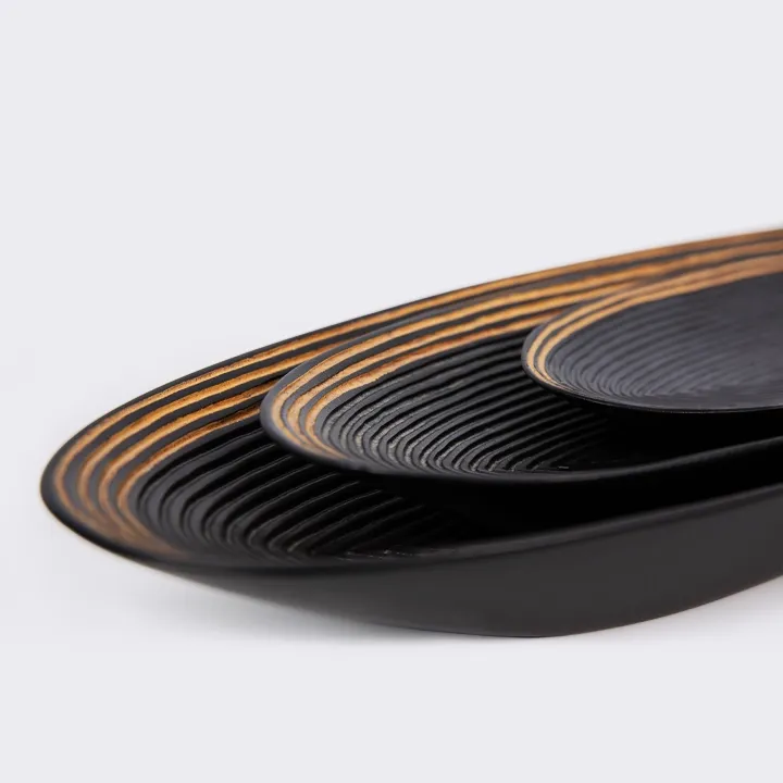 Oval tray in exotic wood, handcrafted in Madagascar, with a textured, ribbed black surface.