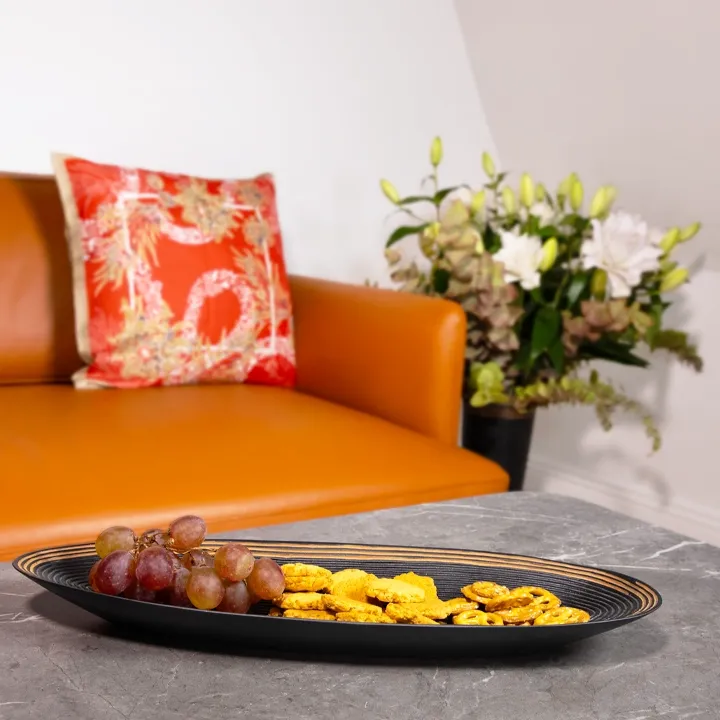 Oval tray in exotic wood, handcrafted in Madagascar, with a textured, ribbed black surface.