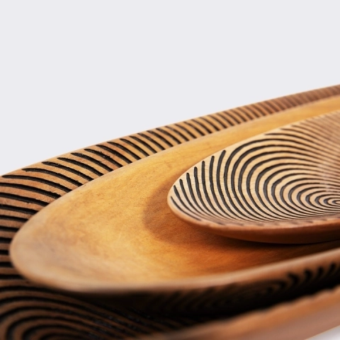 Close-up of the 'Lakana' wooden tray, featuring hand-carved concentric circle patterns resembling water ripples