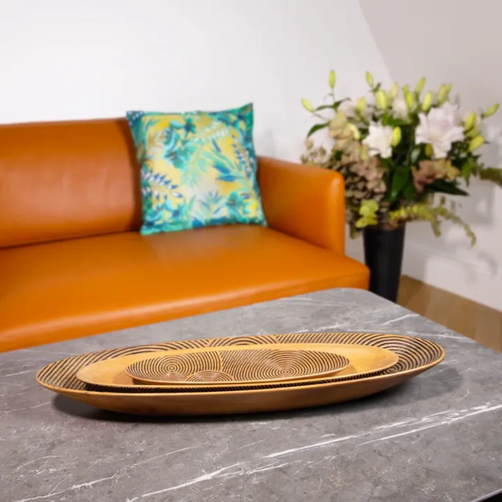 Set of three nesting oval wooden serving trays with black graphic engravings, inspired by traditional Madagascar canoes.