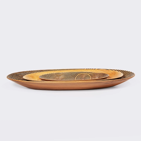 Set of three nesting oval wooden serving trays with black graphic engravings, inspired by traditional Madagascar canoes.