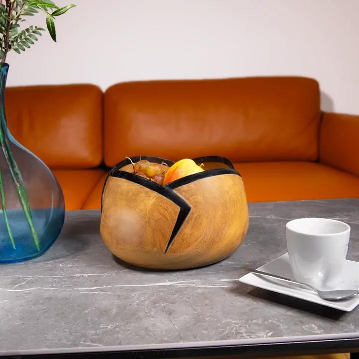 Modern centerpiece: Sculptural wooden fruit bowl with black accents, filled with grapes and oranges.