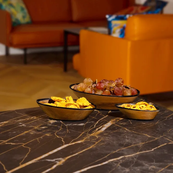 Rotating view of the Set of three nesting oval exotic wood bowls with a sleek modern design and black painted rim.